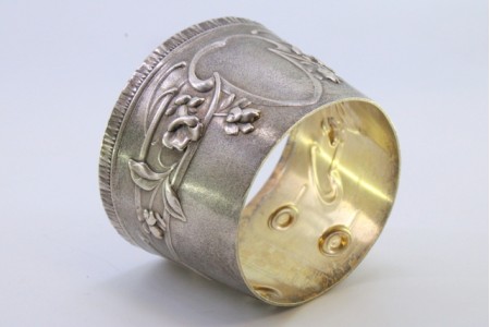 Argola de guardanapo em prata em forma de punho, relevada com motivos florais envolvendo cartela para monograma.